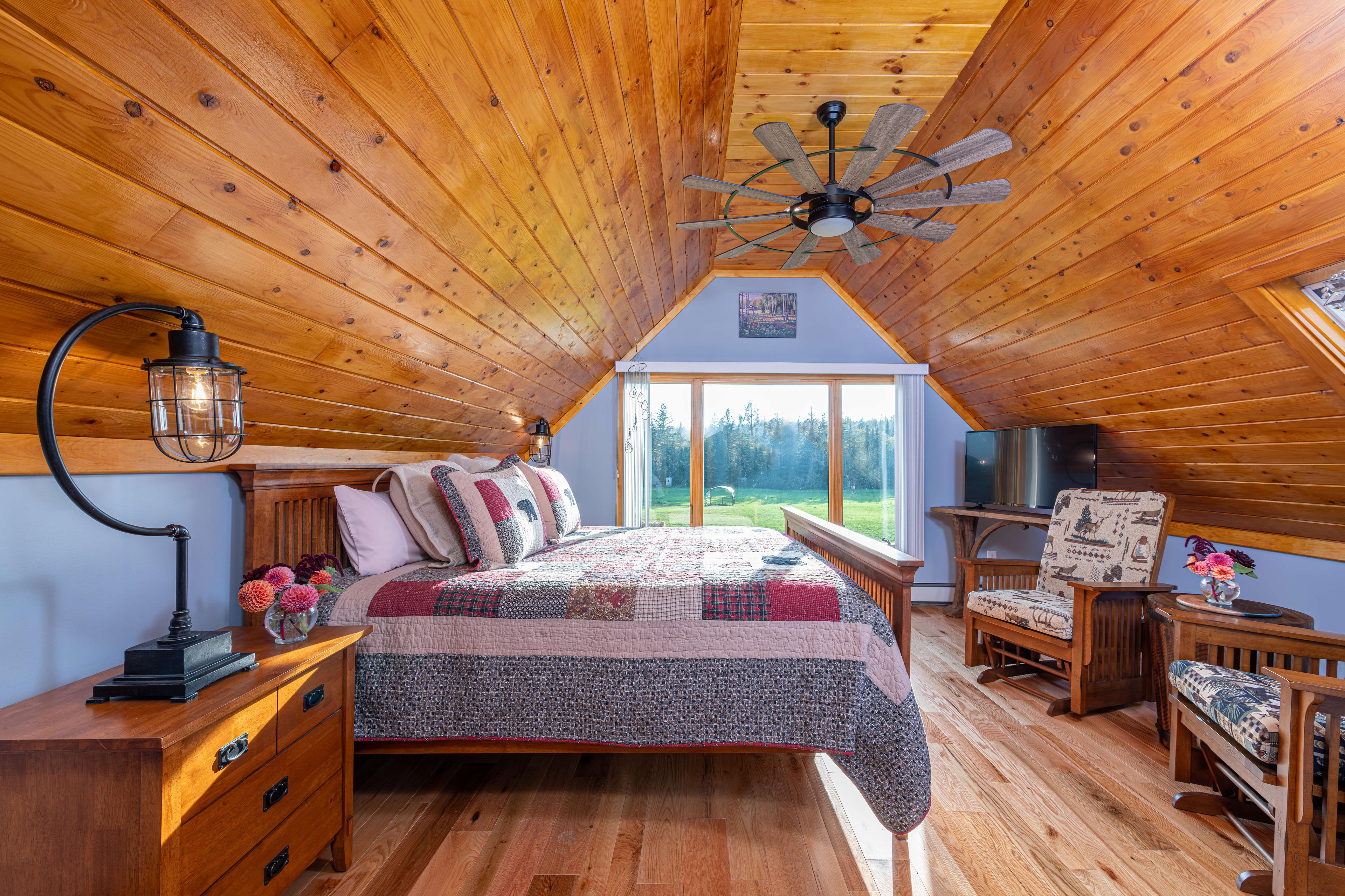 Picture of a bedroom with beautifully finished wood ceilings and floors,king size wooden bed with bears on the bedspread