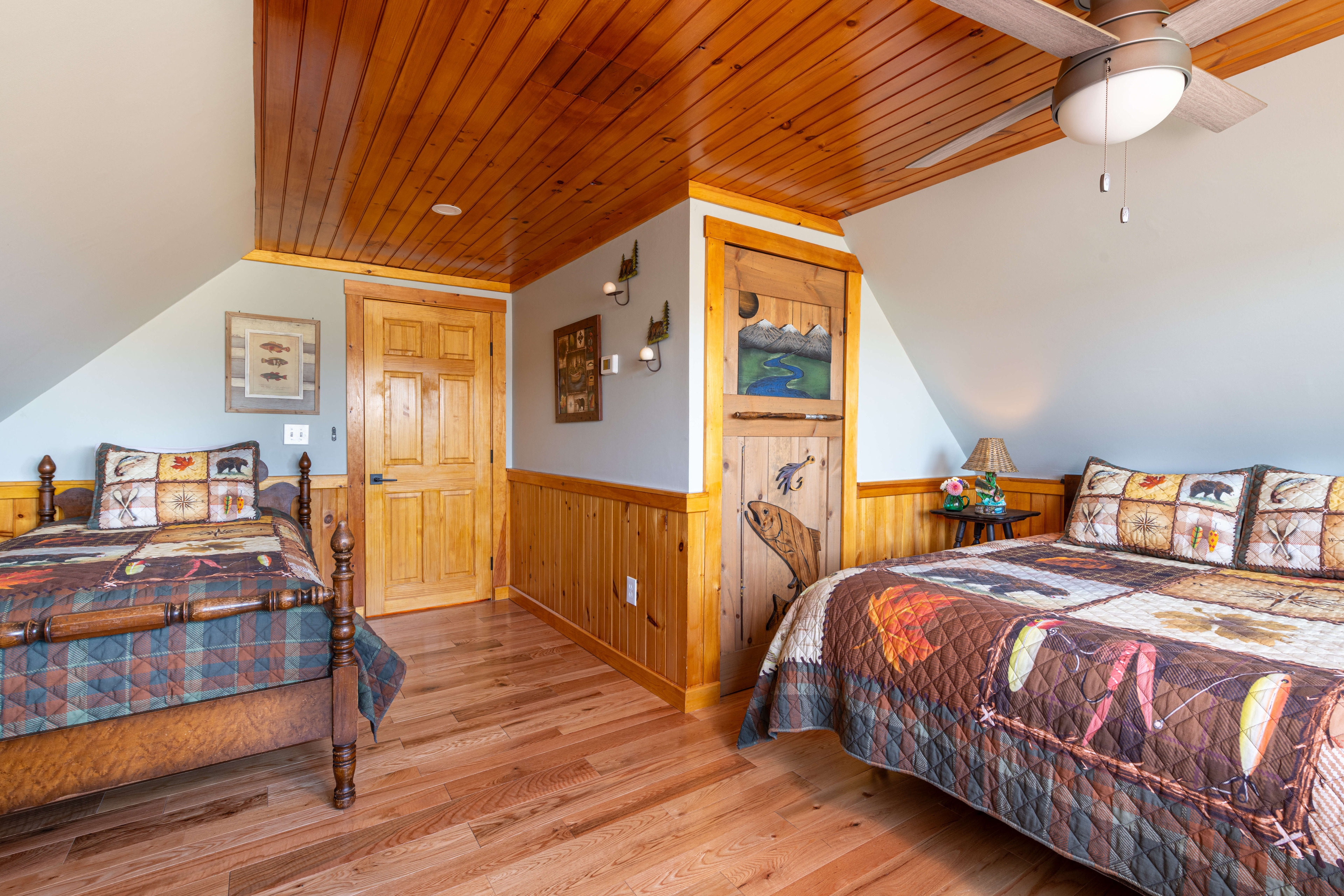 Queen and twin bed with rustic-patterned quilt and a wooden door with a fish