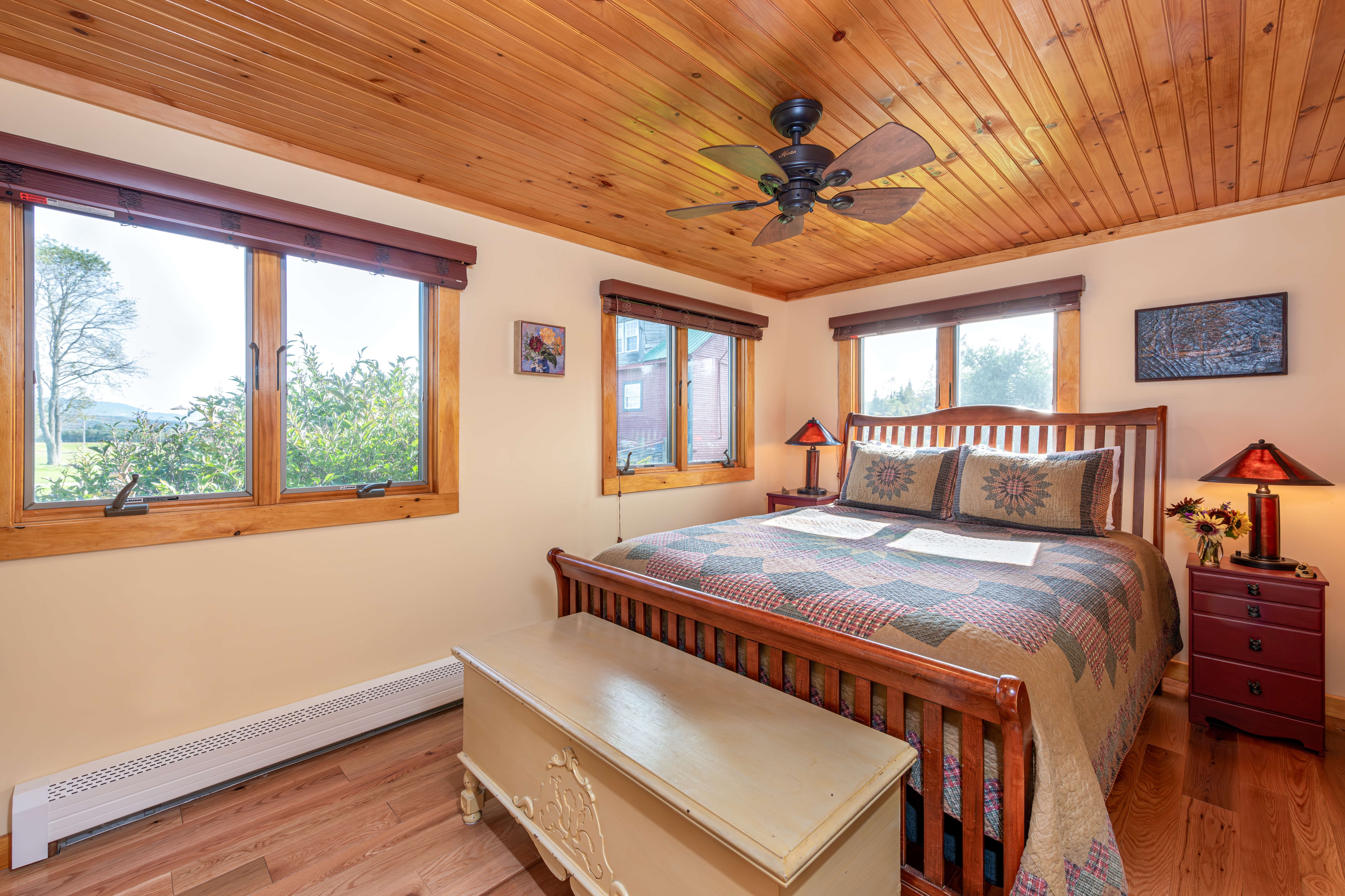 Sleigh bed with yellow wooden chest, wooden ceiling with fan