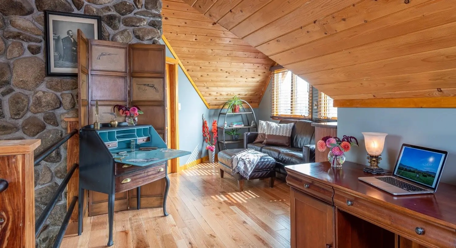 Interior view with stone and wood walls, sitting area, fold down desk and computer on side table