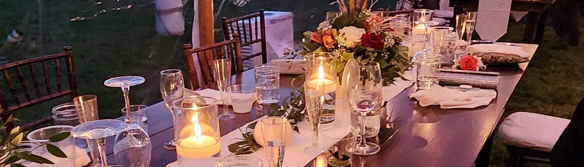 A wedding table in a reception tent full of wine glasses and floral centerpieces