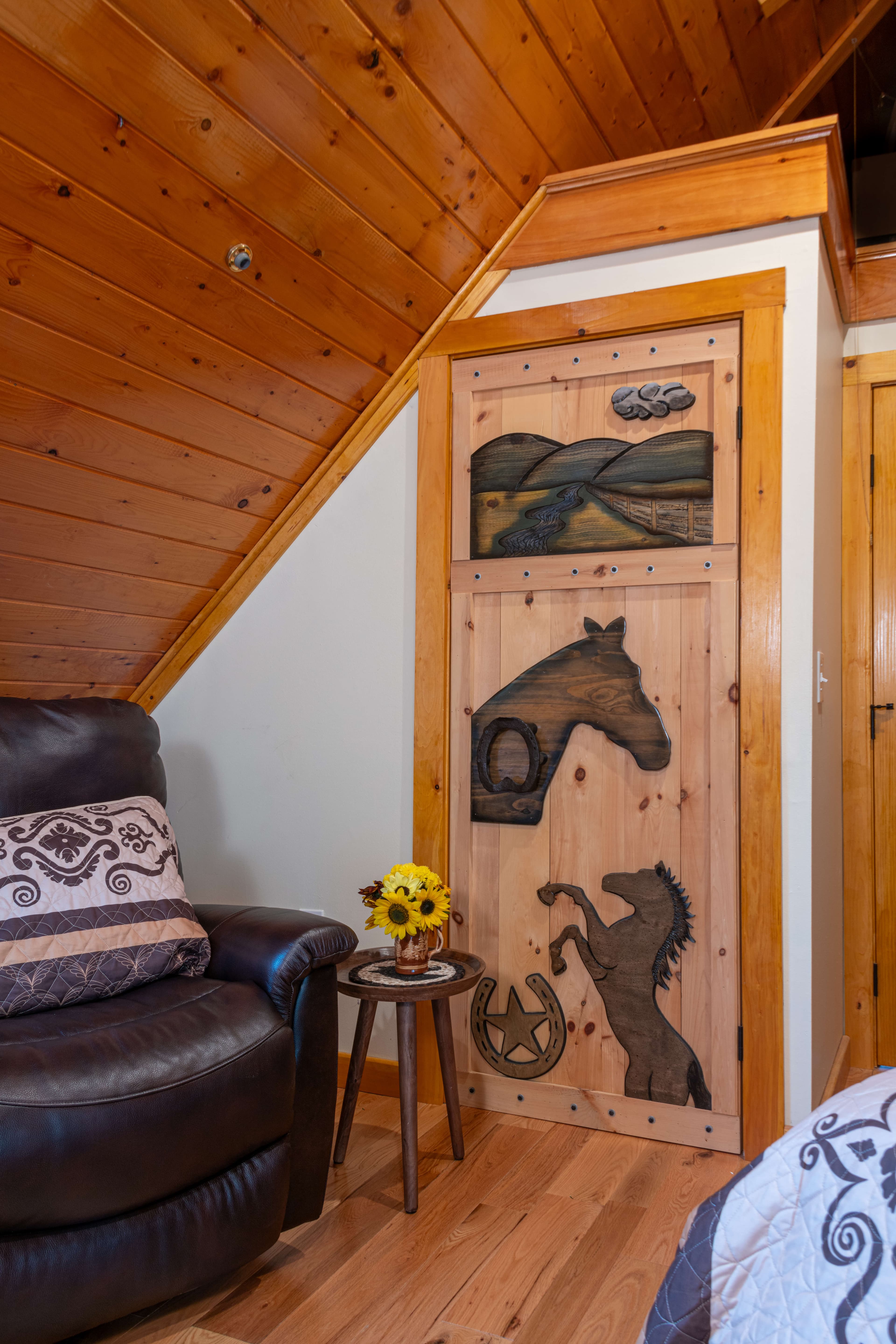 Dark brown recliner with southwest-style throw pillow and uniquely carved door with horses