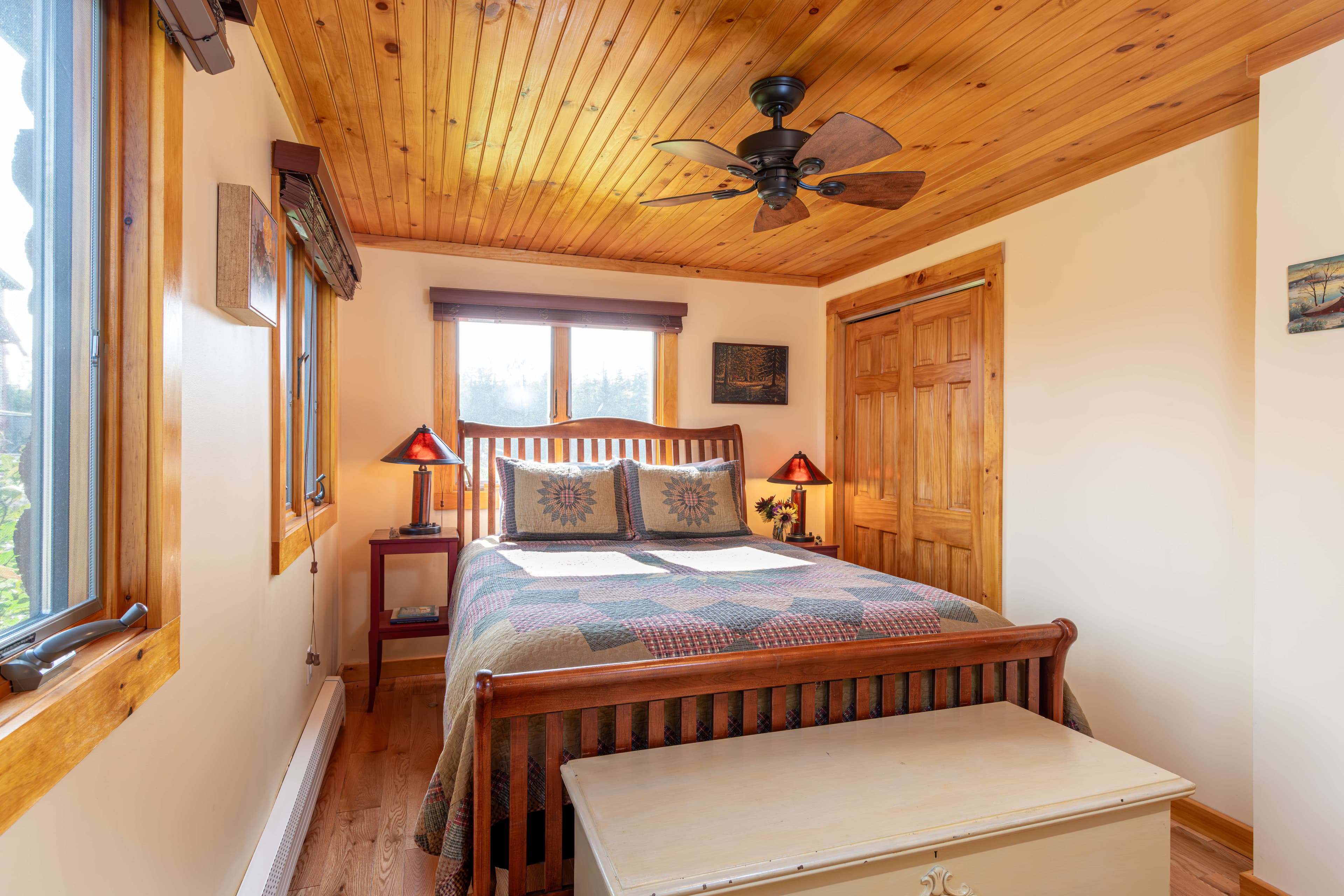 Sleigh bed with sunflower quilt and two bedside lamps, wooden ceiling with fan