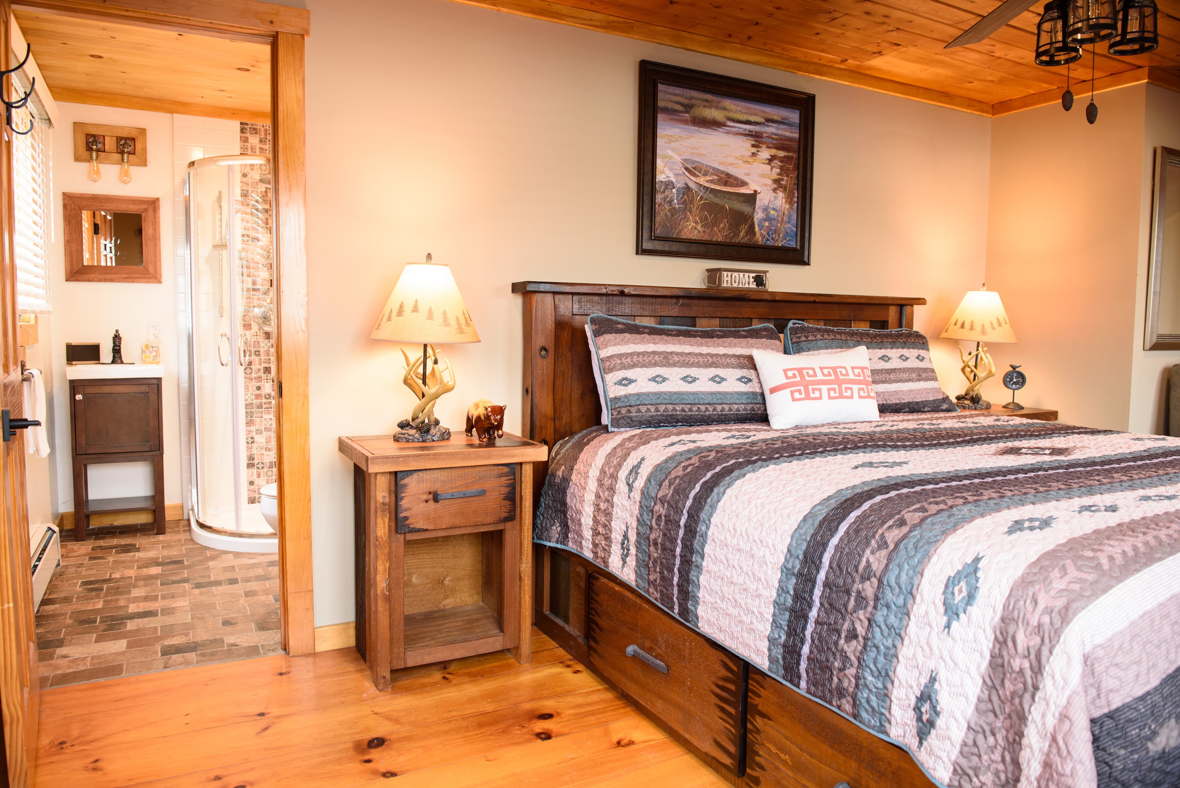 King Captain's bed flanked by nightstands and lighted lamps. The doorway looking into the bathroom is to the left.