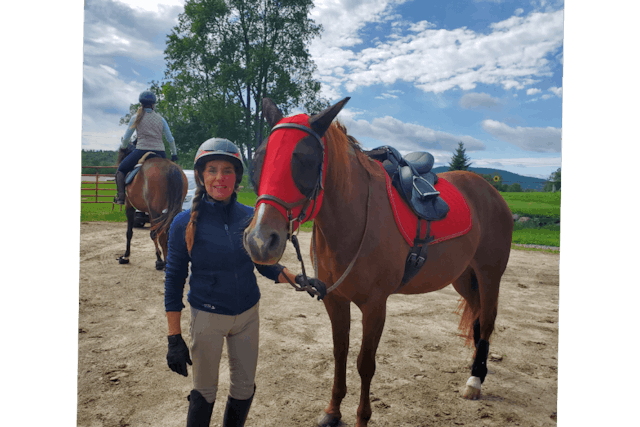 A woman standing next to a horse wearing a red hood