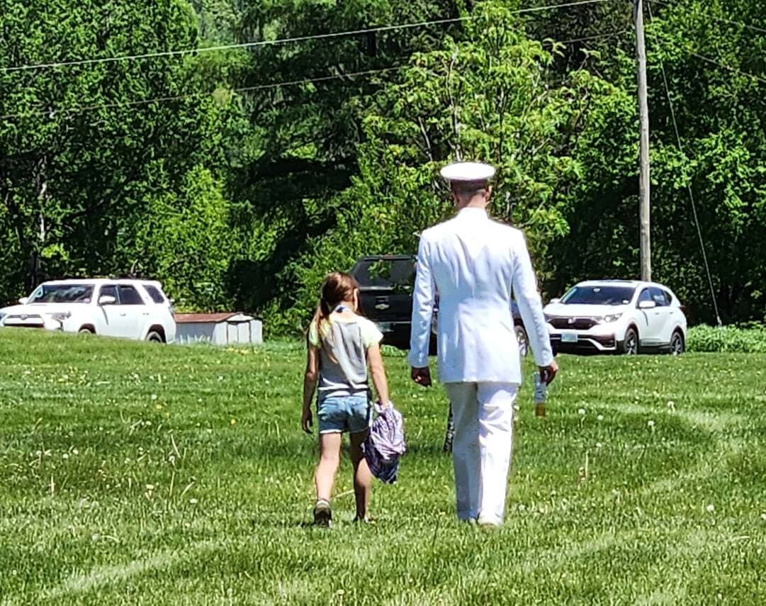 A soldier in a white uniform with a little girl next to him