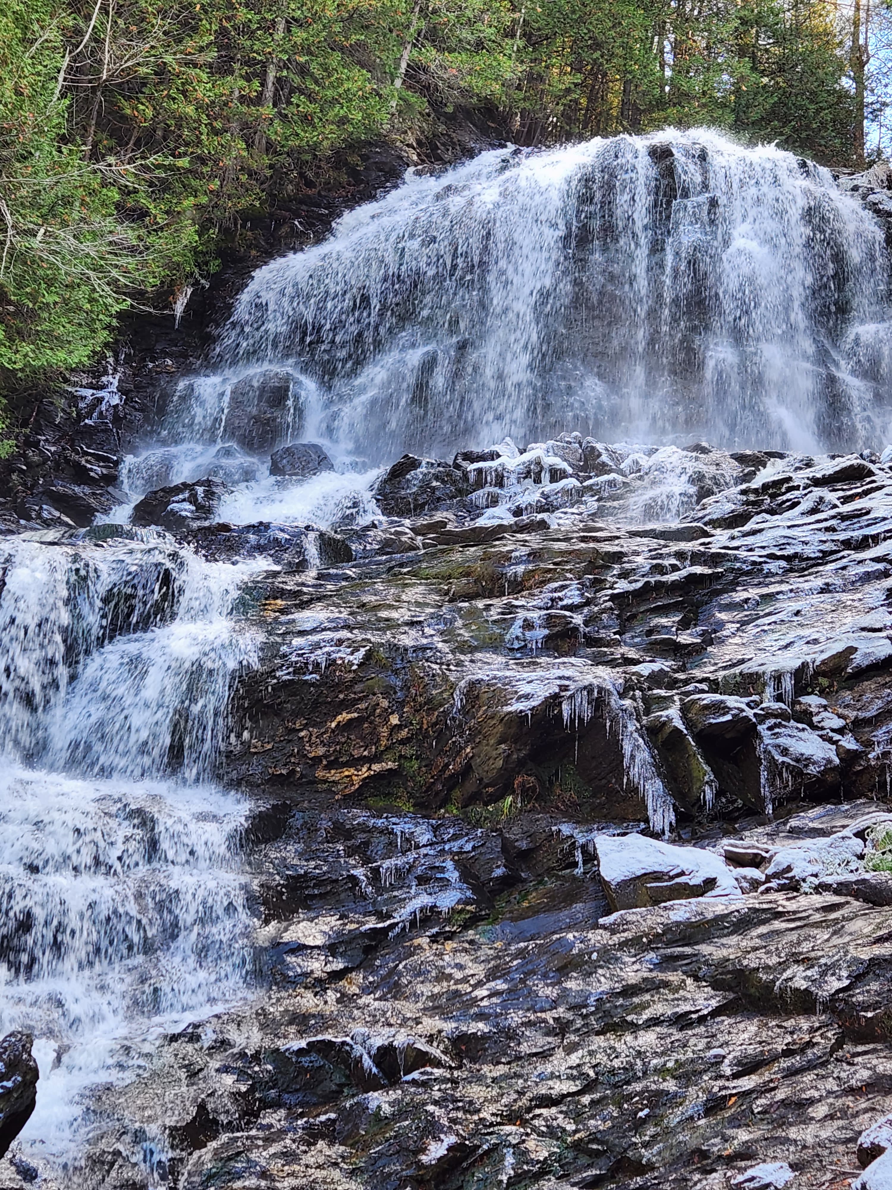 Large waterfall cascading over rocks in the middle of a forest